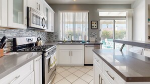 A modern kitchen with white cabinets, a stainless steel stove, and a tiled backsplash. - Chic Cathedral City Home with Private Pool & Spa | Minutes to Palm Springs (Cathedral City)