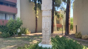 Ein Steins Denkmal in einem Innenhof, umgeben von Bäumen und einem Gebäude.