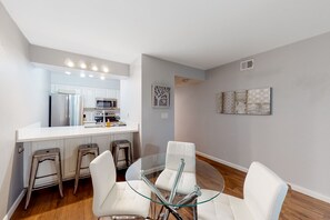 A modern kitchen with white cabinets, stainless steel appliances, and a glass dining table with white chairs. - Old Town condo with balcony, pool, spa, grills/picnic area, & W/D (Scottsdale)