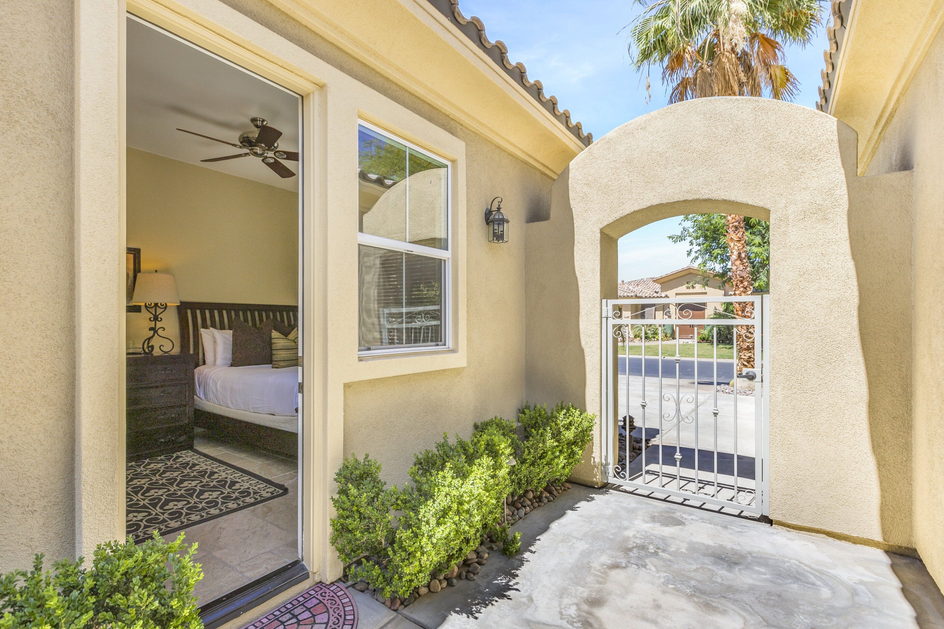 A residential entryway with a door, a small garden, and a view of a bedroom.