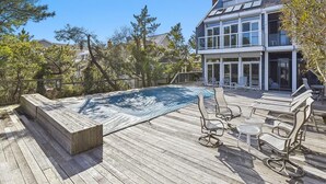 Una casa moderna con terraza, mobiliario exterior y piscina.