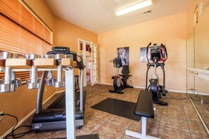 Ein Fitnessstudio mit Trainingsgeräten, darunter Laufbänder, Crosstrainer und eine Bank.