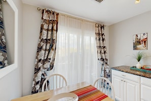 A dining area with a table, chairs, a window with curtains, a kitchen counter, and a potted plant. - Bright Tucson home near golf & hiking with pool & spa - 30-night stay min. (Tucson)