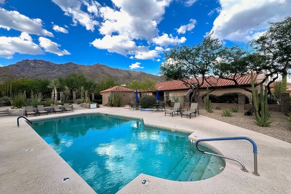 Una piscina con cielo azul despejado y montañas al fondo.