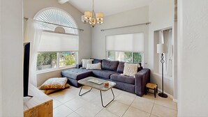 Ein modernes Wohnzimmer mit einer Eckcouch, einem Couchtisch und einer Pendelleuchte.