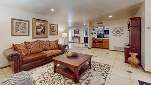A living room with a brown leather sofa, a wooden coffee table, and a patterned rug. - 4 BR house with pool, putting green, great patio (Scottsdale)