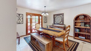 A dining area with a wooden table, chairs, a bench, a chandelier, and a bookshelf. - 4 BR house with pool, putting green, great patio (Scottsdale)
