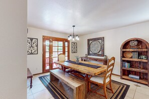 A dining area with a wooden table, chairs, a bench, a chandelier, and a bookshelf. - 4 BR house with pool, putting green, great patio (Scottsdale)