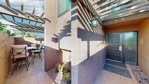 En terrasse med udendørs møbler, en dør med metalgitter og et pergola-konstruktion.