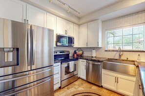 A modern kitchen with stainless steel appliances, white cabinetry, and a herringbone-patterned backsplash. - Step-free, dog-friendly home with pool, hot tub & grill (Scottsdale)