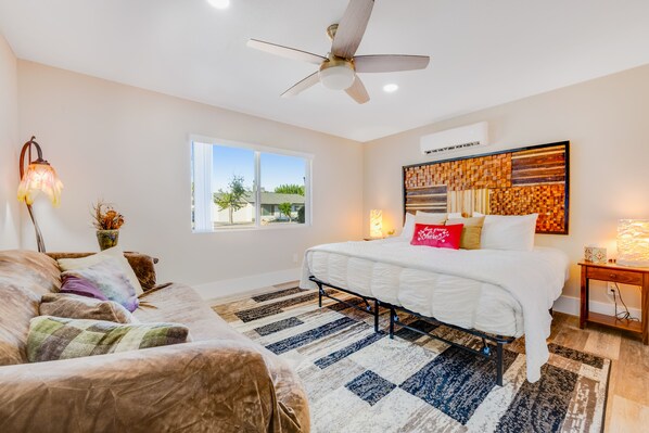 A bedroom with a bed, a ceiling fan, a window, and a wall art piece. - Enchanting home with private hot tub, putting green, yard & washer/dryer (Scottsdale)