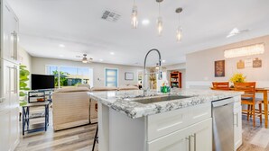 Een moderne keuken met een marmeren eiland, witte kasten en een inbouw vaatwasser.