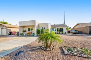 A residential area with modern houses, a driveway, and a small palm tree. - Enchanting home with private hot tub, putting green, yard & washer/dryer (Scottsdale)