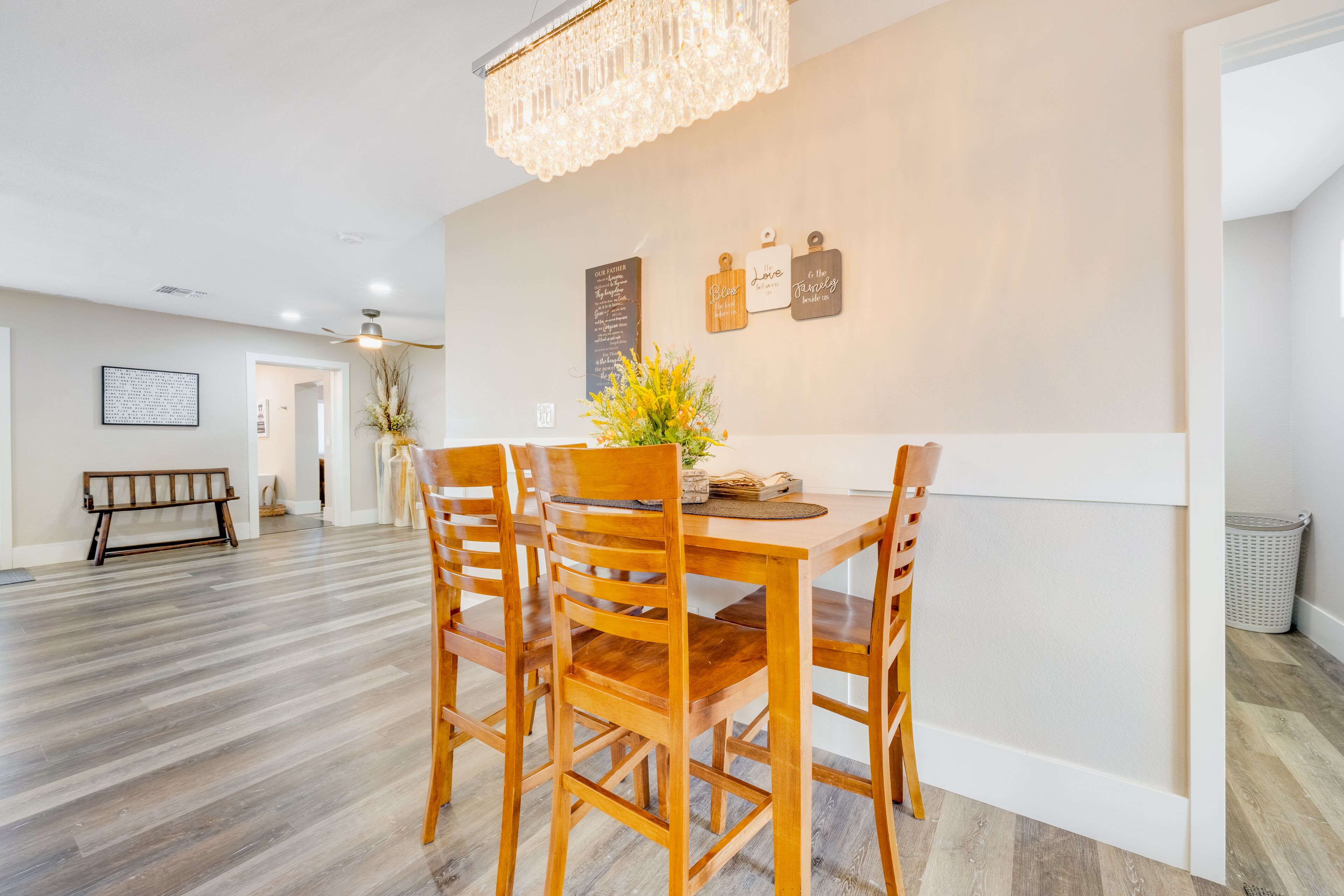 A dining area with a wooden table and chairs, a chandelier, and a wall with decorative plaques.