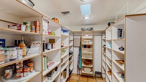 A well-organized pantry with shelves stocked with canned goods, jars, and kitchenware.