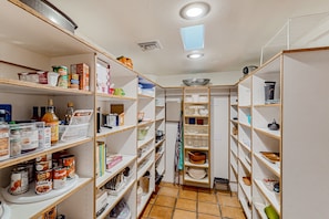A well-organized pantry with shelves stocked with canned goods, jars, and kitchenware.
