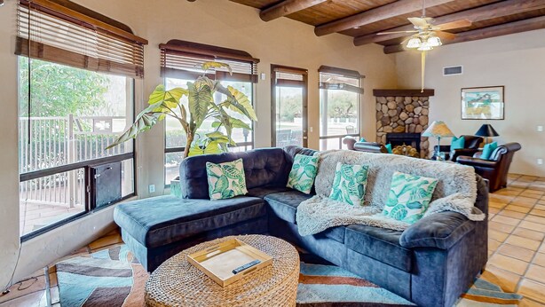 A living room with a dark blue sectional sofa, a woven coffee table, and a ceiling fan.