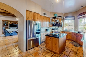 A modern kitchen with wooden cabinets, stainless steel appliances, and a large island. - Golf & mountain view desert home with shared pool and gym - dog-friendly (Tucson)