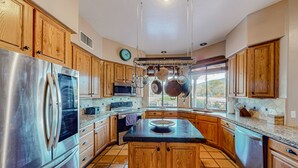 A modern kitchen with wooden cabinets, stainless steel appliances, and a large island.