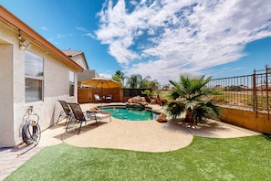 Ein Garten mit Swimmingpool, einer Terrasse mit Stühlen und einem kleinen Wasserfall.