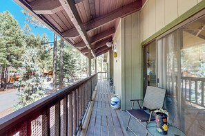 Eine Holzdielen-Terrasse mit Geländer, einem Stuhl, einem Tisch und einem großen Propangasbehälter.
