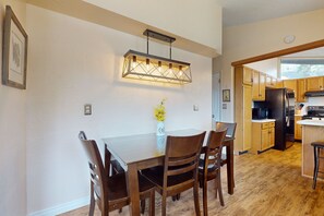 A dining area with a wooden table and chairs, a pendant light fixture, and a vase with flowers. - Shadow Mountain Village Escape | 2 Living Areas, Deck & Yard | Walk to Trail (Flagstaff)