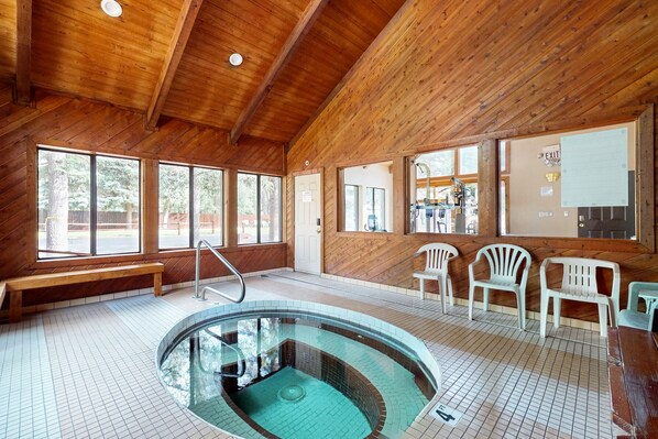 Un intérieur en bois avec une piscine, des bancs et des chaises en plastique.