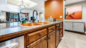 A modern kitchen with granite countertops, wooden cabinets, a double sink, and a dining area with a table and chairs. - Lovely, Ground-Floor Townhouse with a Great Location, Patios, WiFi & Shared Pool (Carefree)