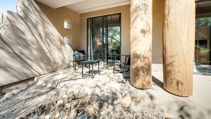 A modern outdoor seating area with stone steps, wooden columns, and a glass door leading to a covered patio. - Lovely, Ground-Floor Townhouse with a Great Location, Patios, WiFi & Shared Pool (Carefree)