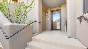 A staircase with a metal handrail, beige walls, and a door leading to a balcony. - Lovely, Ground-Floor Townhouse with a Great Location, Patios, WiFi & Shared Pool (Carefree)