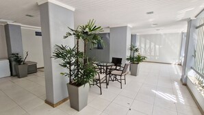 A spacious indoor area with a high ceiling, tiled floor, and several potted plants. - COAPI0100 - Edificio Palais Atlantique (Salvador)