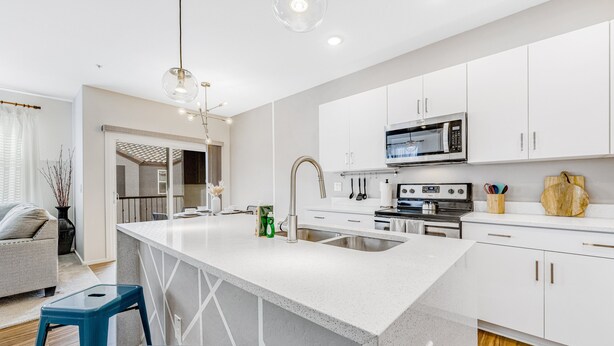 A modern kitchen with white cabinets, a large island, stainless steel appliances, and blue stools. - Charming Condo with Central A/C & Washer/Dryer - Shared Pool & Hot Tub (Phoenix)