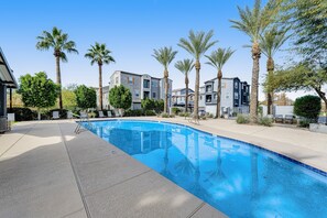 A swimming pool with a clear blue water, surrounded by palm trees and a building with balconies. - Charming Condo with Central A/C & Washer/Dryer - Shared Pool & Hot Tub (Phoenix)