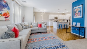 A modern living room with a grey sectional sofa, a patterned rug, and a kitchen in the background. - Charming Condo with Central A/C & Washer/Dryer - Shared Pool & Hot Tub (Phoenix)