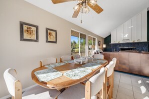 A dining area with a wooden table and chairs, framed artwork on the wall, and a view of the outdoors. - Refined home with a game room, balcony, grill, washer/dryer, & four bedrooms (Flagstaff)