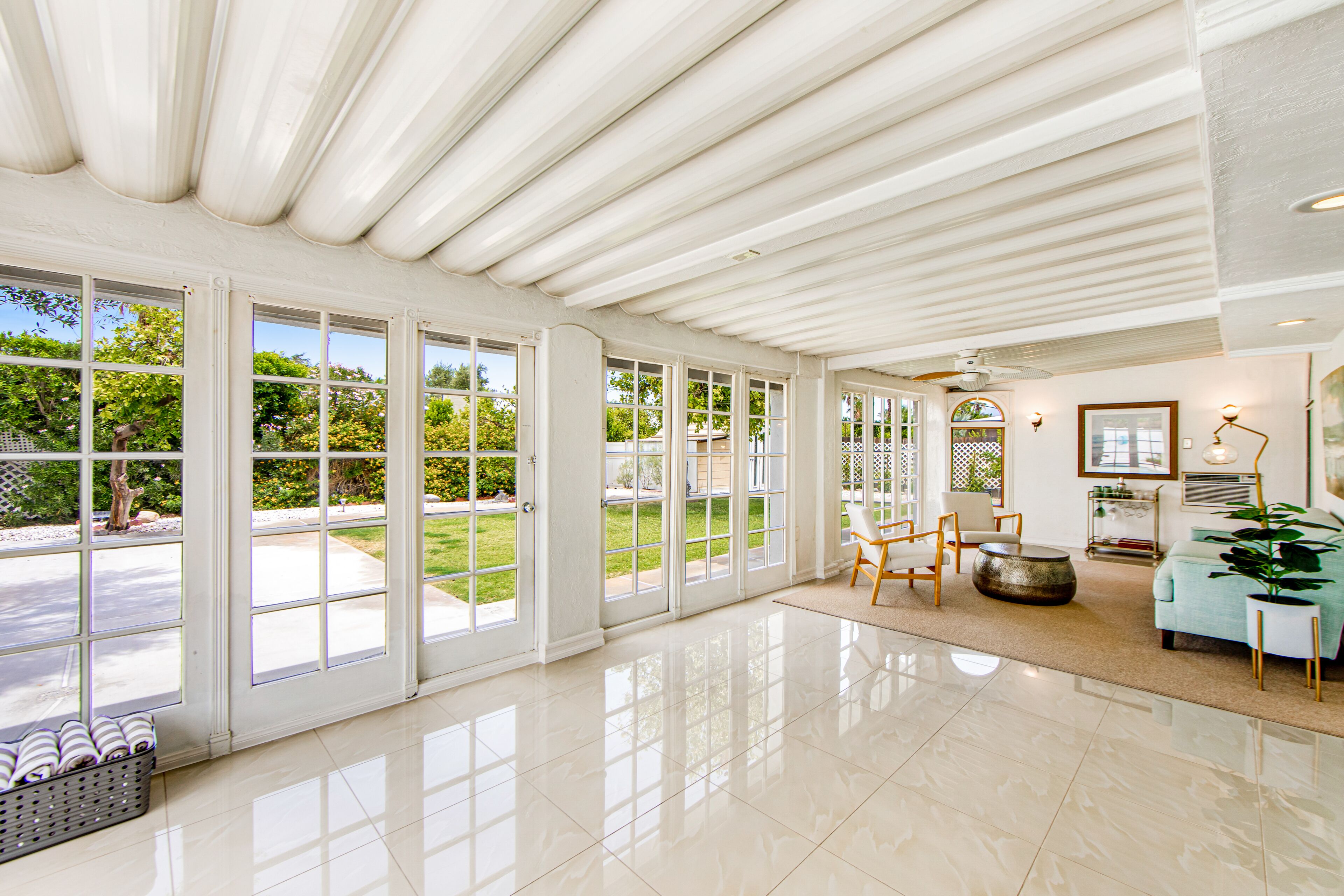 A spacious living room with large windows, a fireplace, and a view of the garden.