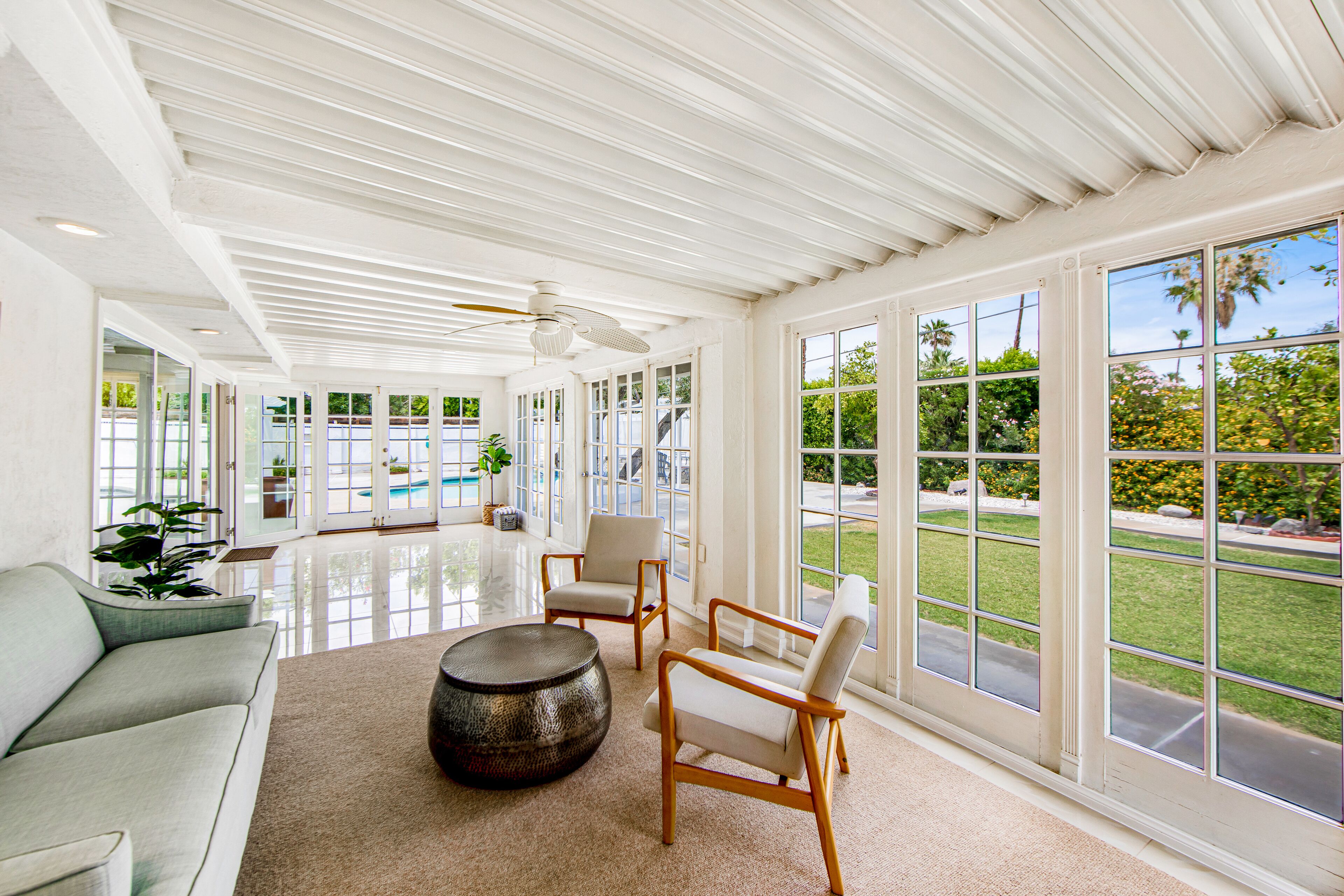 A spacious room with a large window, a ceiling fan, and a sofa.