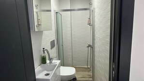 Une salle de bain moderne avec un lavabo blanc, des toilettes et une douche à parois de verre.