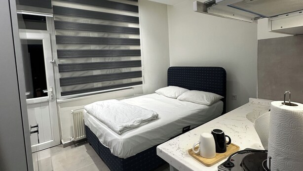Une chambre à coucher moderne avec un lit, une table de chevet et une fenêtre avec des stores.