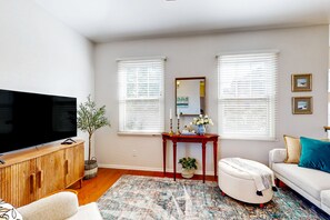 A living room with a flat-screen TV, wooden cabinet, white sofa, and a patterned rug. - Classy house near trails with pools, playground, basketball & beautiful upgrades (Gilbert)