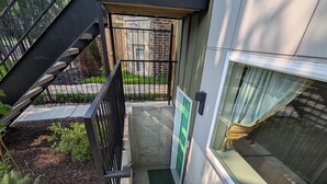 Una escalera de hormigón con barandillas metálicas que lleva a una puerta verde.