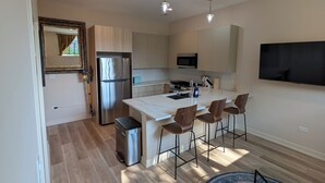 Una cocina moderna con una isla central, electrodomésticos de acero inoxidable y un televisor de pantalla plana en la pared.