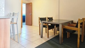 Un comedor con una mesa de vidrio, cuatro sillas y un banco de madera.
