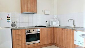 Una cocina con armarios de madera, horno empotrado, microondas y lavamanos.