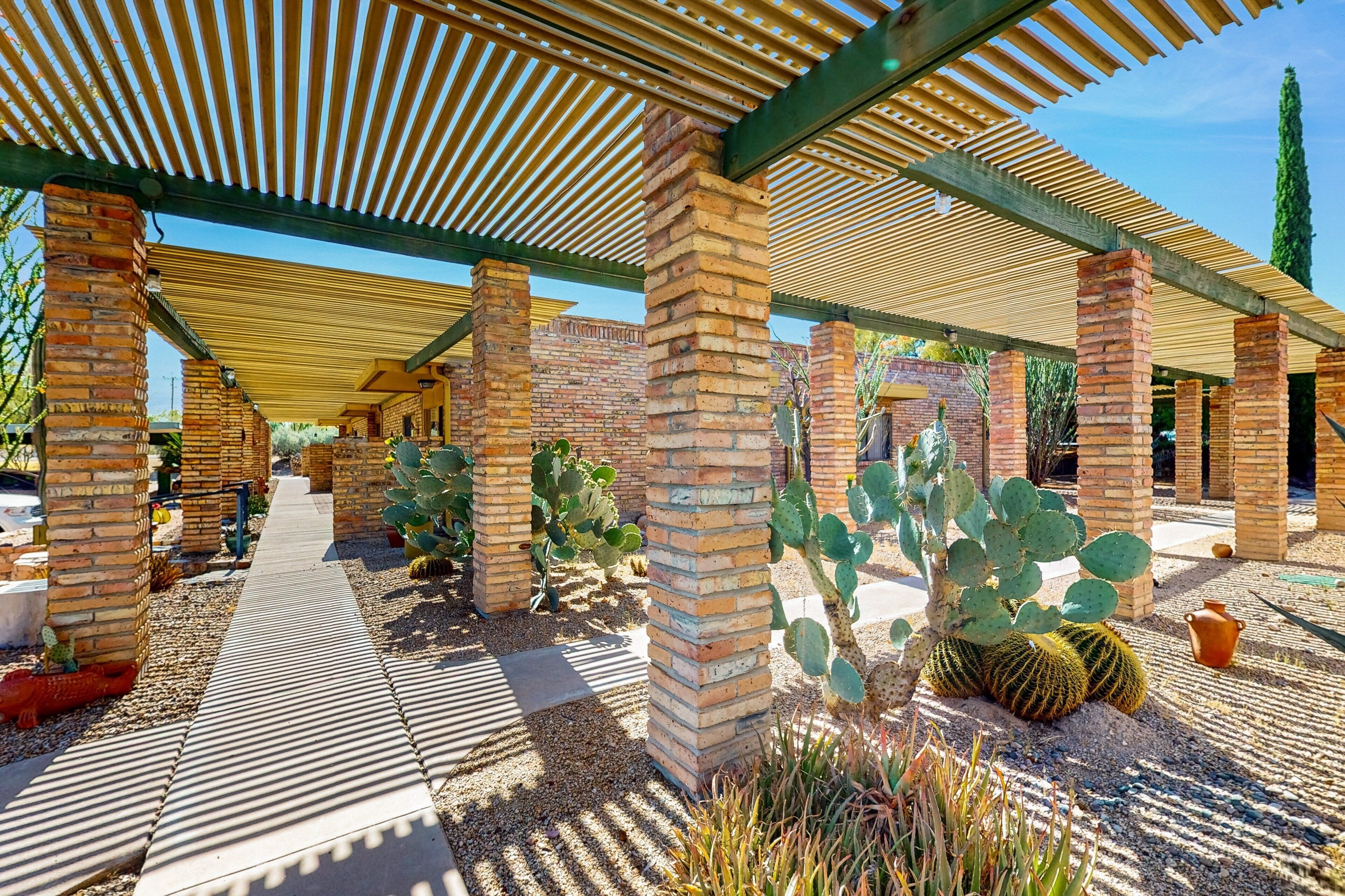 A covered outdoor area with brick pillars, cactus plants, and a pathway.