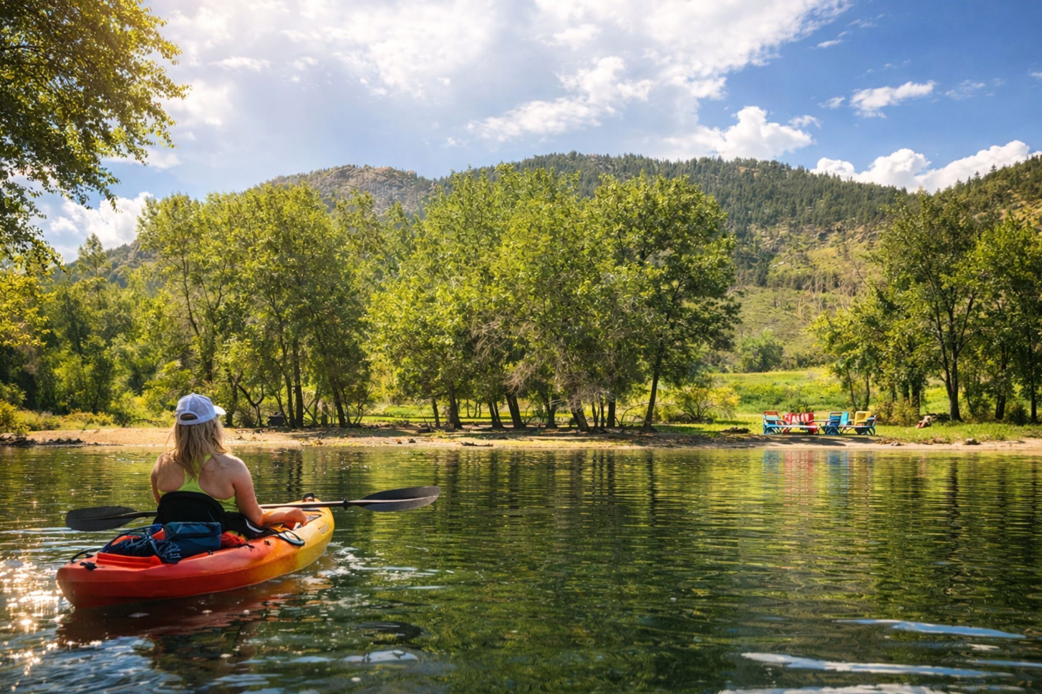 A kayaker on a river with a forested hillside in the background.