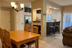 A dining area with a wooden table and chairs, a kitchen with white cabinets, and a living room with a brown sofa. - Remodeled getaway with pool & hot tub - near hiking & town (Oro Valley)