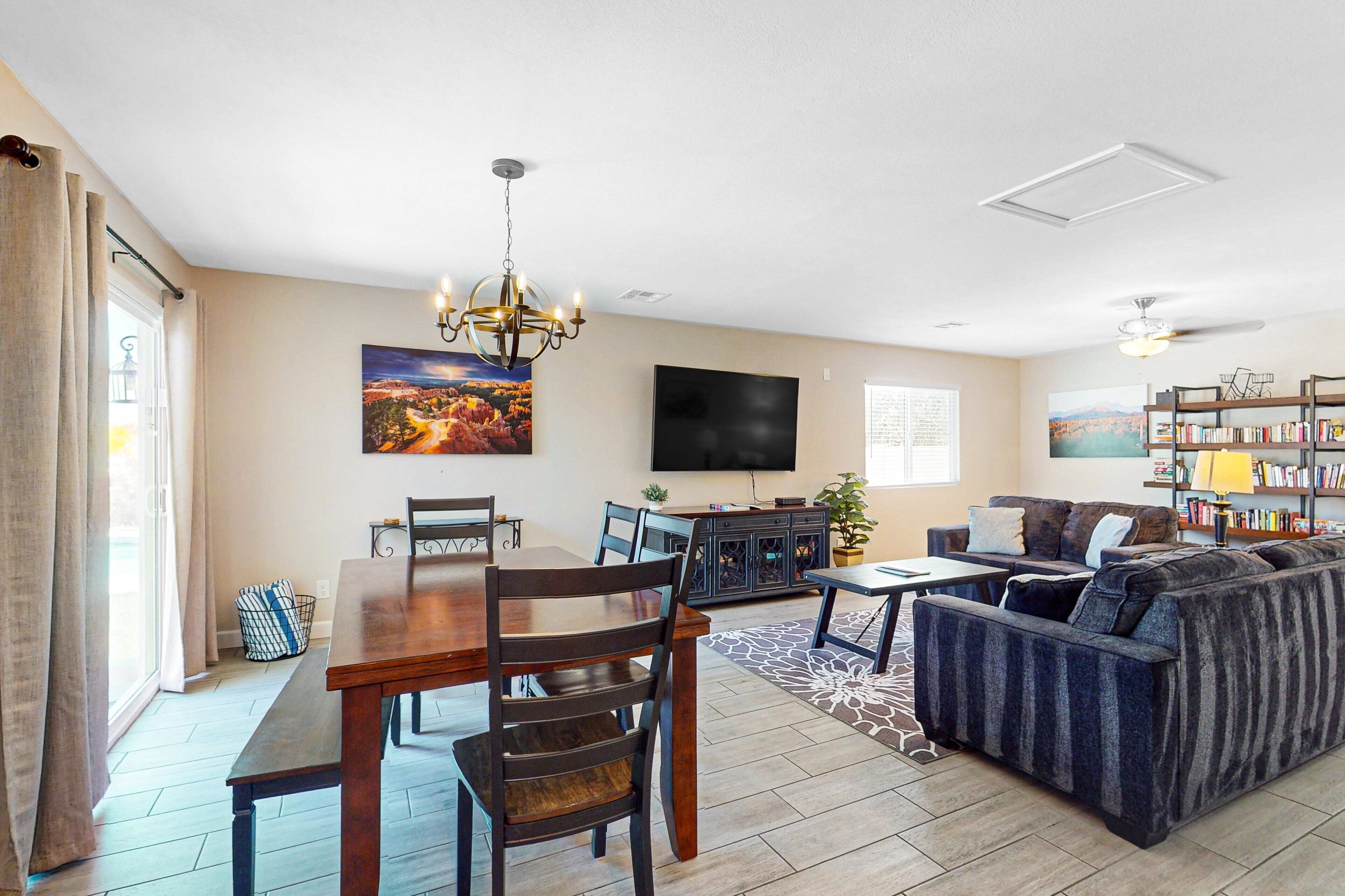 A living room with a dining table, sofa, TV, bookshelf, and a painting on the wall.