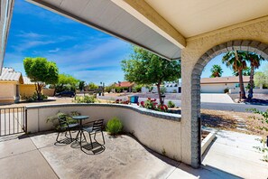 A covered patio with a curved stone wall, outdoor seating, and a view of the neighborhood. - Luxe getaway with private heated pool, patio, and mountain views - walk to park (Fountain Hills)