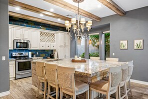 A modern kitchen with a central island, bar stools, and a chandelier. - Snowbird-Friendly Home with Private Pool, Grill, AC, Fireplace, & WiFi - Dogs OK (Glendale)